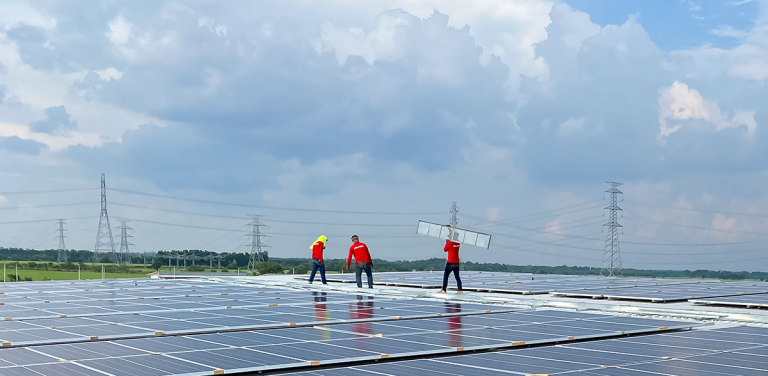 Workers installing solar panels on a rooftop under a cloudy sky, with power lines visible in the background.