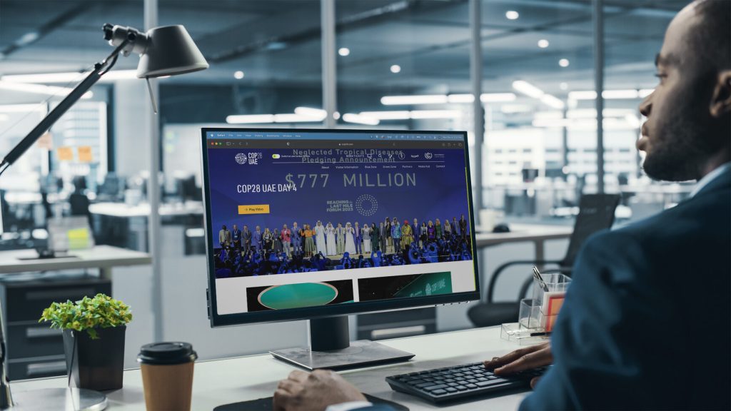A person sitting at a desk, focused on a computer screen displaying financial figures and images in a modern office environment.