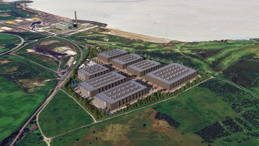 Aerial view of modern industrial buildings situated near the coastline, surrounded by green landscape and waterways.